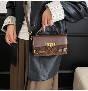 Detail der braunen Vintage-Umhängetasche mit goldener Schnalle am Model-Outfit