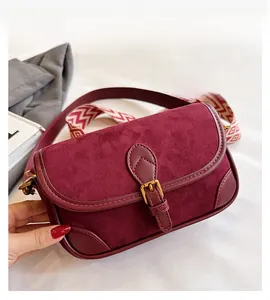 Details der burgunderroten Satteltasche mit Wildlederstruktur und gewebtem Tragegurt