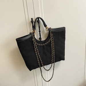 Borsa tote trapuntata nera con catena dorata e manici, vista appesa in stile elegante