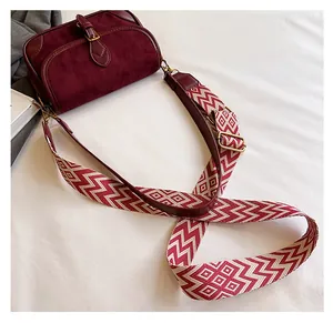 Detail der weinroten Baguette-Tasche mit geometrischem Jacquard-Gurt und Goldbeschlägen