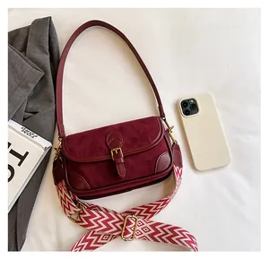 Detail der burgunderroten Wildledertasche mit goldener Schnalle und gewebtem Trageriemen