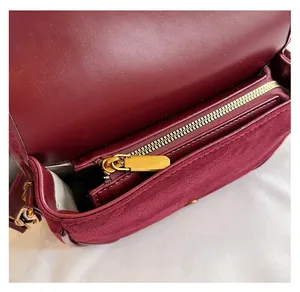 Nahaufnahme des goldenen Reißverschlusses und Wildlederfutters der burgunderroten Tasche