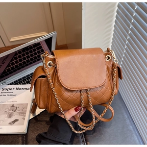 Detailed close-up of caramel brown quilted leather backpack with gold chain straps