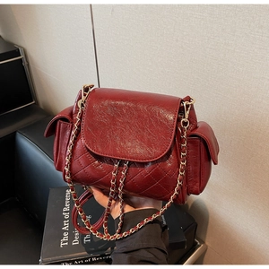 Detail of burgundy quilted leather bag with side pockets and golden chain strap