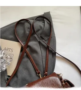 Detail of smooth brown leather shoulder strap with gold metal buckle on a quilted bag