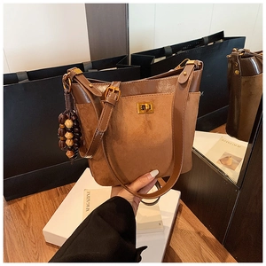 Detail of brown vintage shoulder bag with golden twist lock and beaded charm accessory