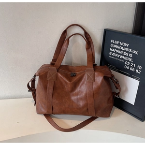 Detailed close-up of brown textured leather Boston bag with vintage hardware and handles