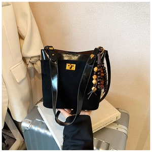 Detail of black patchwork handbag with gold square lock and vintage wood bead charm