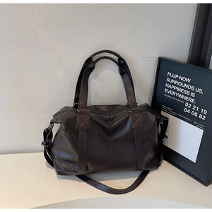Detail of dark brown faux leather pillow bag with top handles and adjustable strap