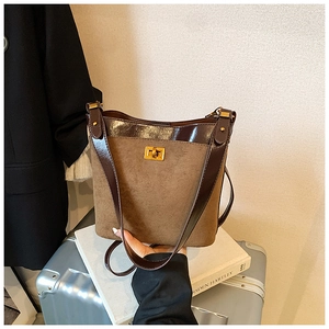 Detail of vintage suede shoulder bag featuring a gold metal twist lock and dual leather texture