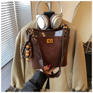 Detail of suede and leather crossbody bag with golden twist lock and beaded charm