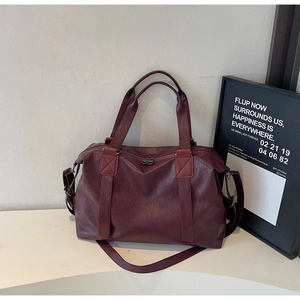 Detail of dark burgundy faux leather pillow bag with lychee texture and dual zippers