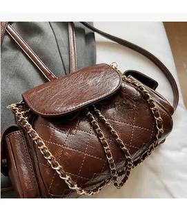 Close-up of dark brown quilted leather surface with glossy finish and chain detail