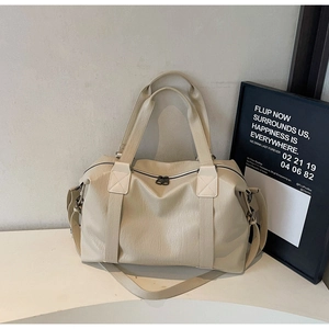 Detail view of large beige faux leather travel bag with wide handles and D-ring hooks