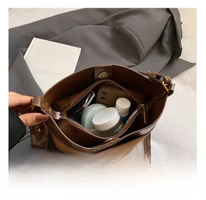 Internal view of brown leather bag showing large capacity with zipper pocket and magnetic buckle
