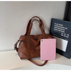 Detail view of large caramel leather pillow bag with adjustable strap and iPad size reference