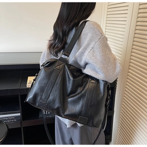 Black large capacity shoulder bag showing back carrying perspective and leather texture