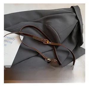 Detail of adjustable leather shoulder strap with bronze metal buckle on brown bag