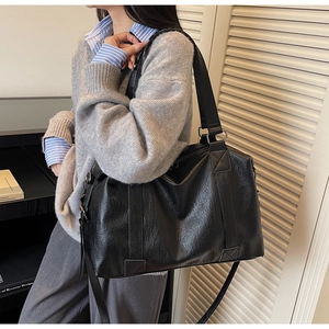 Detailed view of black textured leather bag showing reinforced stitching and silver hardware