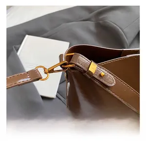 Close-up of golden metal hooks and fine stitching on a dark brown leather shoulder bag