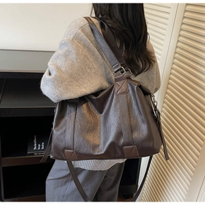 Detail of deep brown faux leather tote bag with dual handles and metal zipper