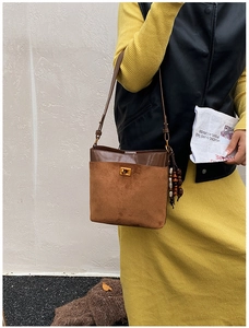 Detail of a brown patchwork shoulder bag with a gold metal lock and vintage wood bead charm