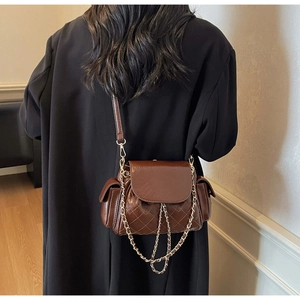 Detail of coffee brown quilted hobo bag with gold metal chain and side pocket design
