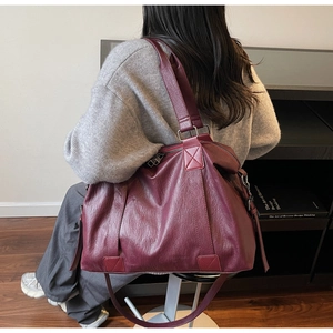 Model wearing a large burgundy hobo bag with fringe detail in a modern home interior