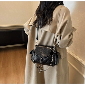 Detail of black quilted shoulder bag featuring oil-wax texture and chain leather strap