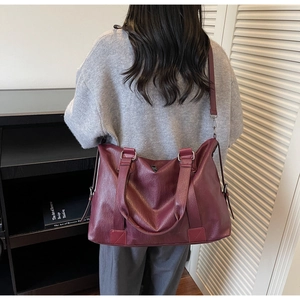 Rear view of a burgundy leather tote bag with pebble texture and adjustable shoulder strap