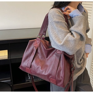 Close-up of a large burgundy tote bag with crinkled faux leather texture and shoulder strap
