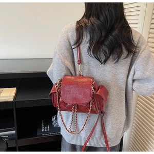 Detail of red quilted faux leather bag with glossy finish and gold chain strap