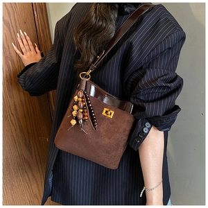 Detail of vintage brown suede shoulder bag with gold clasp and beaded tassel on office suit