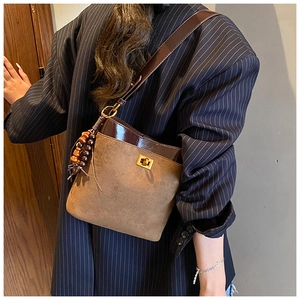 Detail of vintage tote with golden twist lock and decorative wood bead tassel
