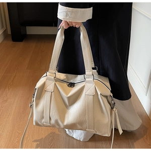 Detail of creamy white faux leather pillow bag showing lychee grain texture and handles
