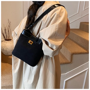 Detail of black crossbody bag featuring matte leather texture and gold twist lock closure