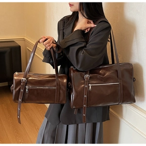 Detail of dark brown leather Boston bag showing glossy texture and strap belt holes