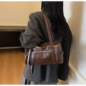 Close-up of deep brown Boston bag showing glossy leather texture and silver zipper detail