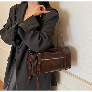 Close-up of dark brown leather Boston bag with silver zipper and adjustable buckle