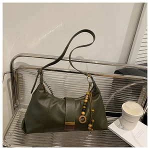 Detail of dark green leather shoulder bag with elegant wooden bead tassel and metal buckle
