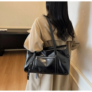 Detail of a black Boston bag with silver metal eyelets on the strap and zip pocket