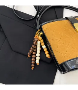 Détail d'un bijou de sac en perles de bois avec fermoir doré sur un sac seau matelassé