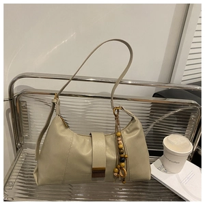 Detail of beige faux leather tote bag with vintage metal buckle and decorative beads