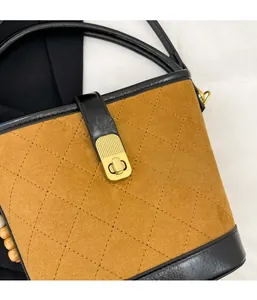 Détail du sac seau vintage en daim marron avec matelassage en losange et fermoir doré