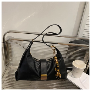 Detail of black leather hobo bag with vintage metal buckle and wooden bead tassel decor