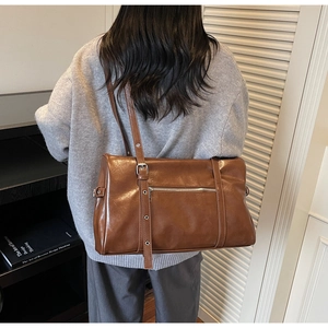 Rear view of a model wearing the brown leather Boston bag with adjustable strap and zip pocket
