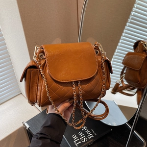 Brown quilted leather shoulder bag with golden chain and side pockets in soft natural light