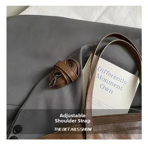 Detail view of adjustable brown faux leather shoulder strap with dark silver hardware