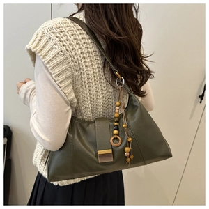 Detailed view of olive green crescent shoulder bag with ethnic beaded tassel and gold lock