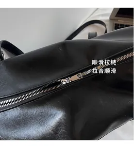 Detailed close-up of the smooth silver zipper and soft black leather texture of the bag